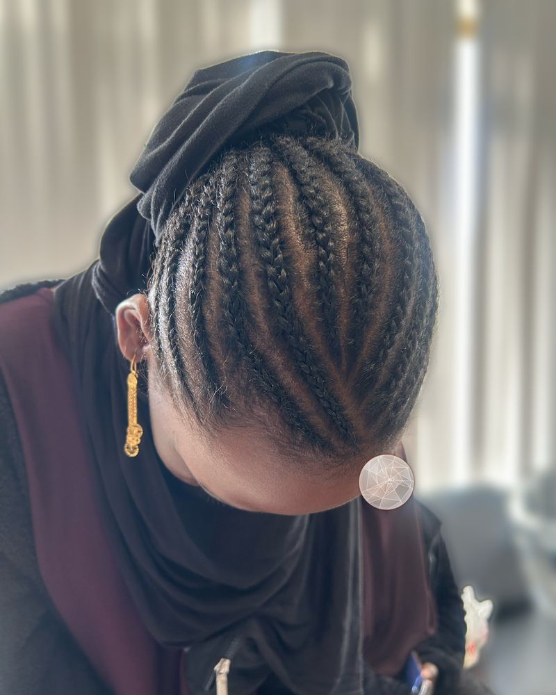 Straight-back cornrows gathered into a bun under a head wrap