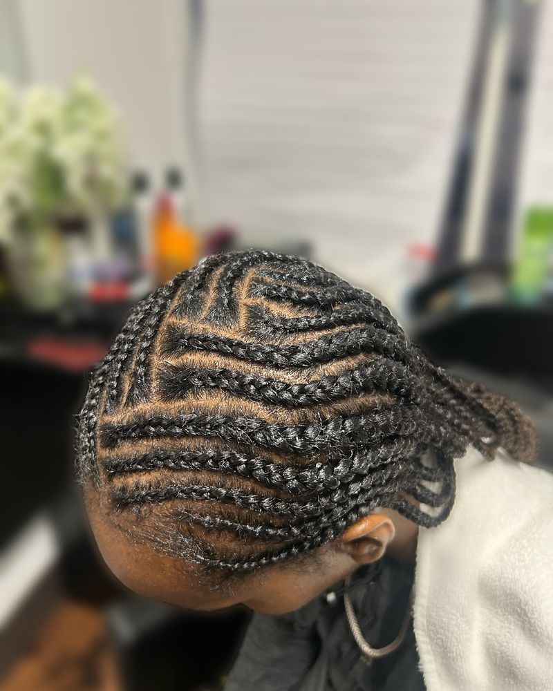 Zig-zag cornrows swept to one side in a wave pattern