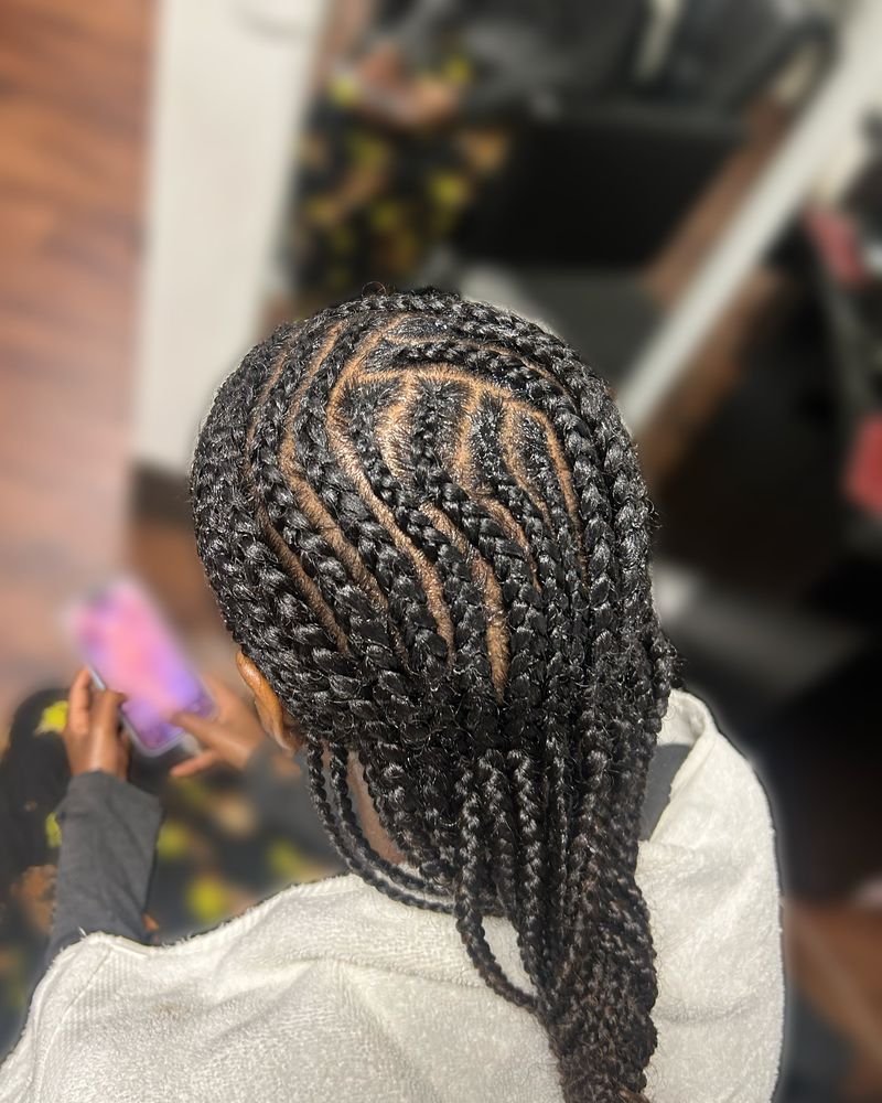 Curved side cornrows flowing into long braids