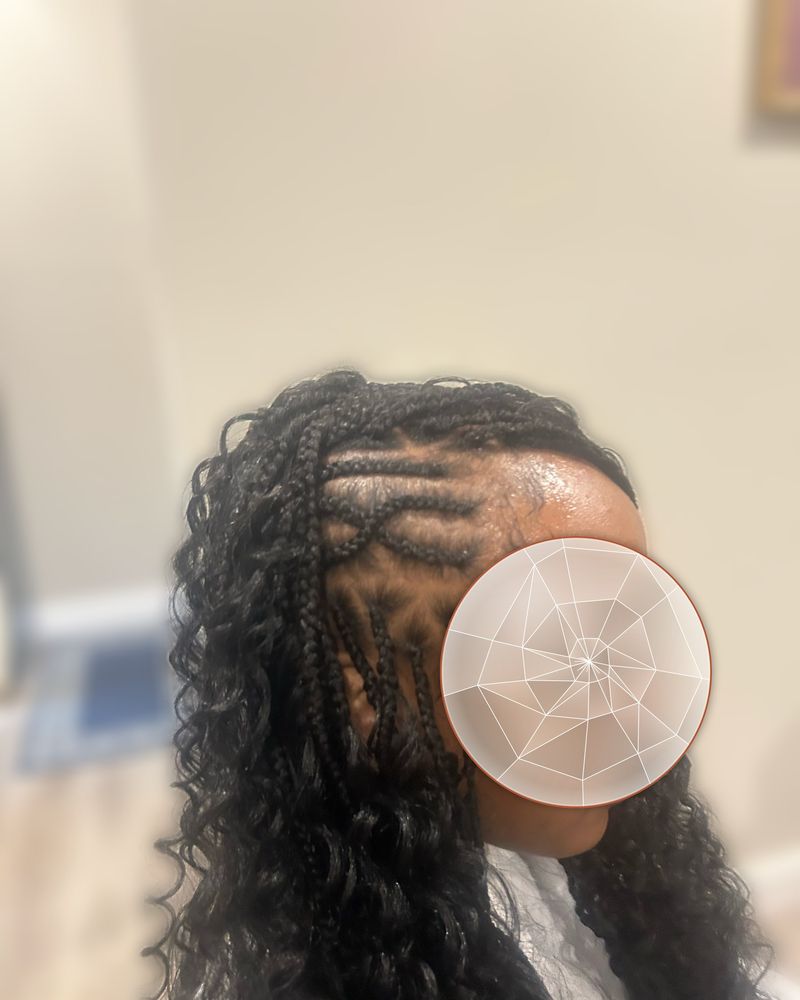 Curved side cornrows with a freestyle design flowing into curly boho braids