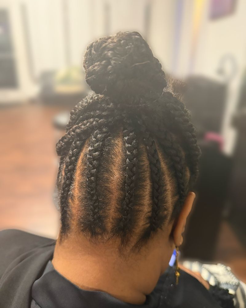 Cornrows swept up into a high braided bun, seen from behind