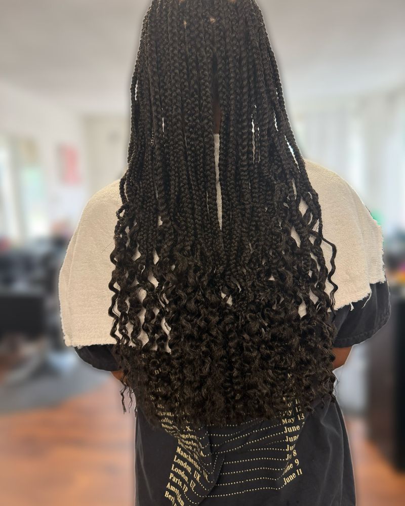 Waist-length boho knotless braids with curly ends, seen from behind